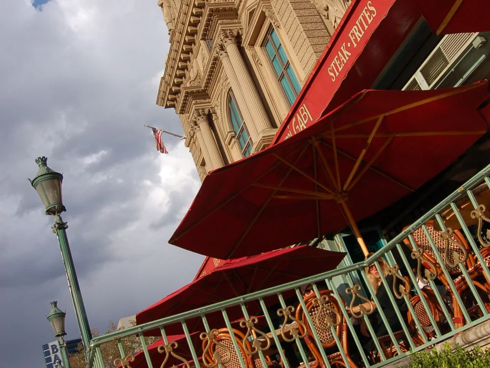 Lively lunch patio crowd sipping rosé under striped awnings